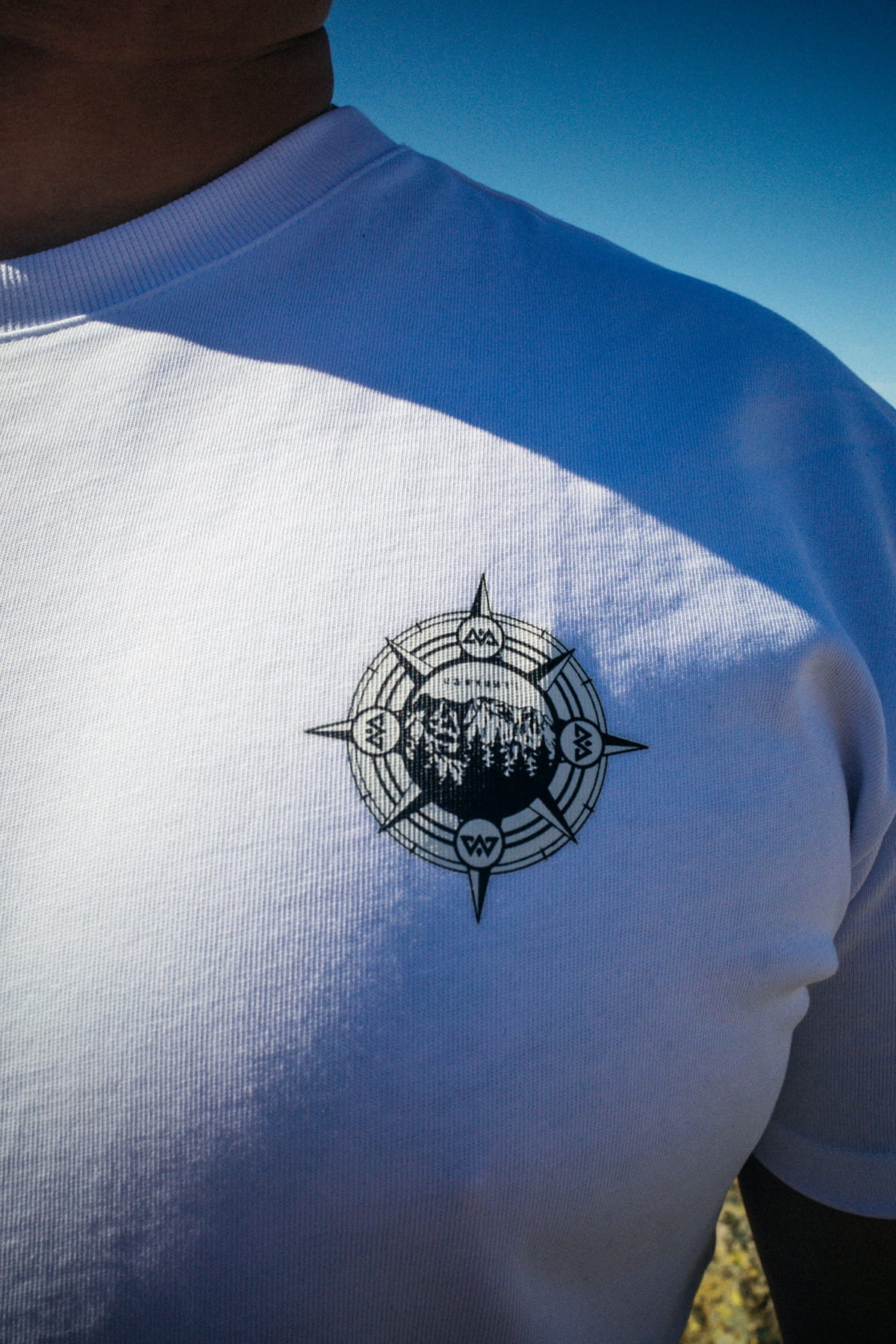 Close-up of small black compass logo on left chest