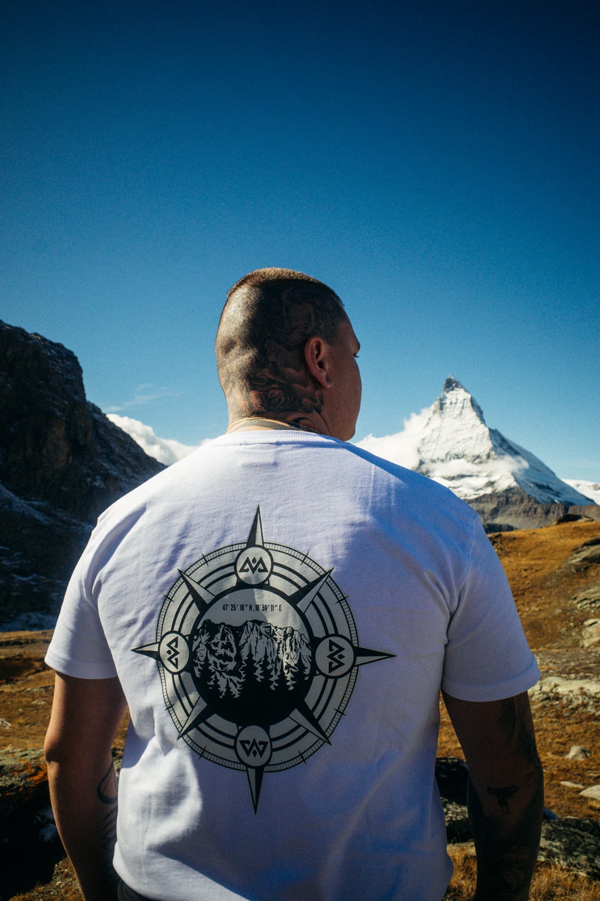 Back view of white Avantura T-shirt with large graphic compass print