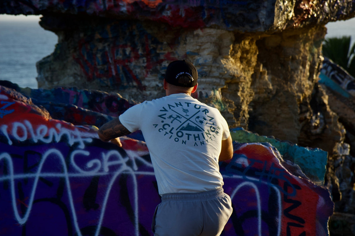 Beige t-shirt with vibrant back print against graffiti wall, emphasizing urban streetwear aesthetic