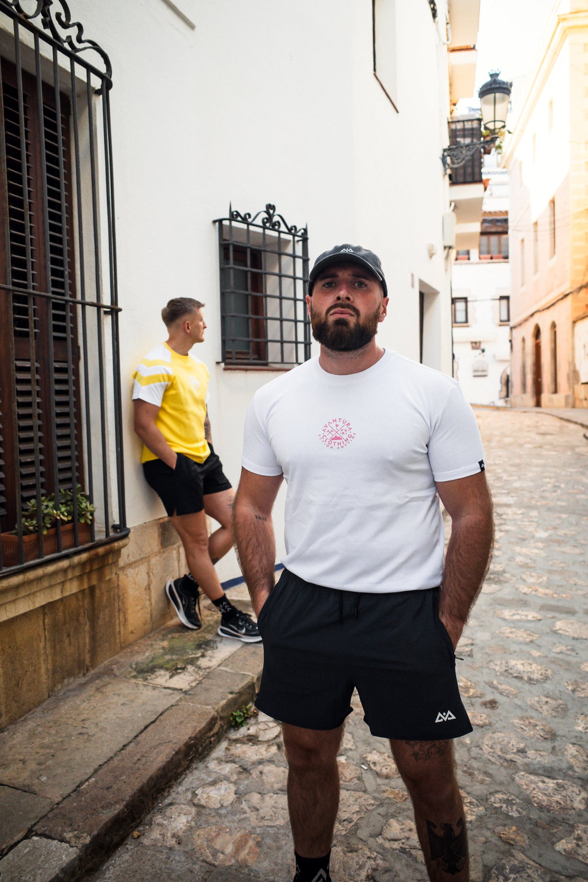 White crew neck t-shirt with small pink logo on chest worn by man in street