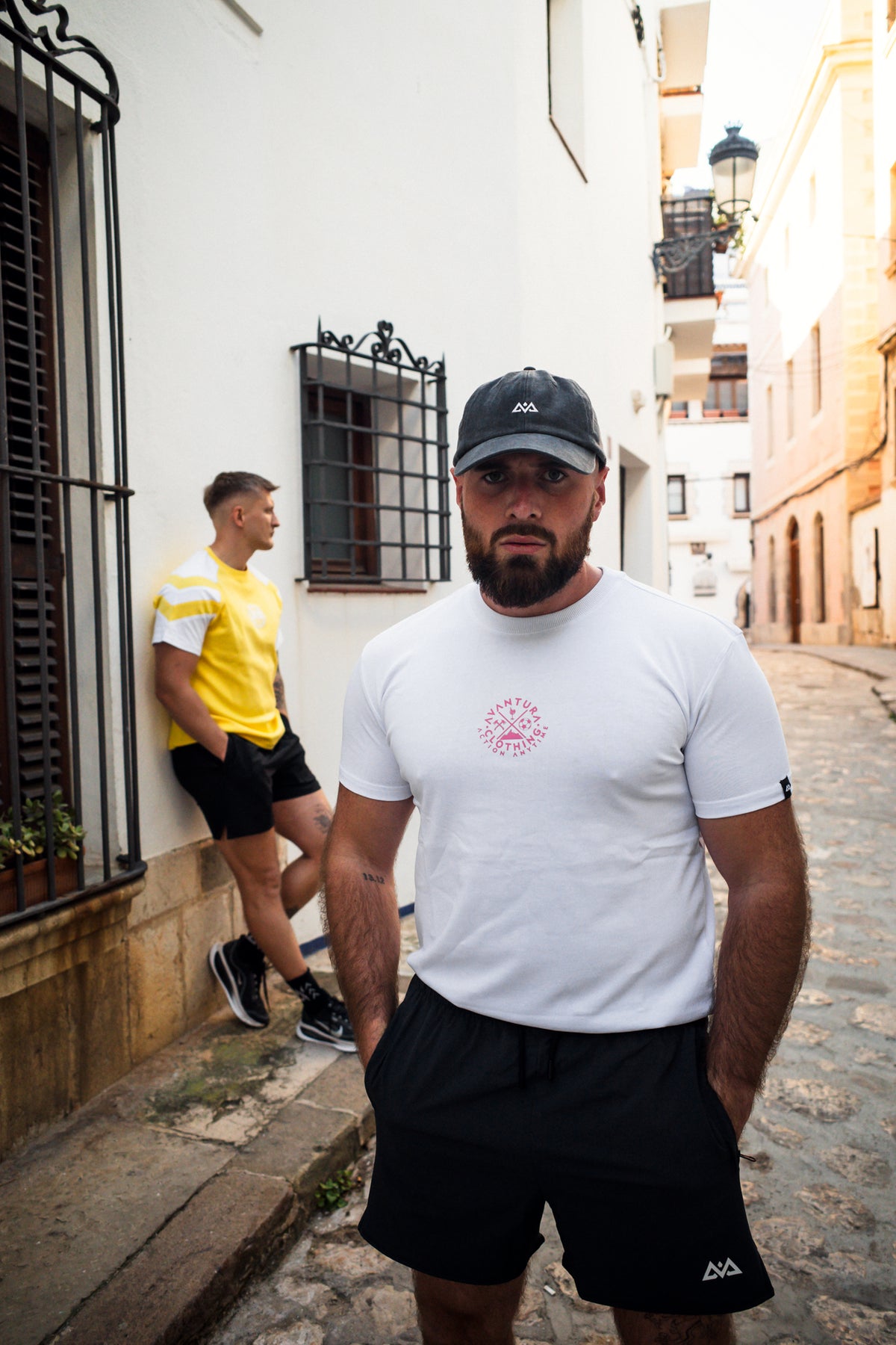 Man wearing white t-shirt with centered pink Avventura clothing logo graphic