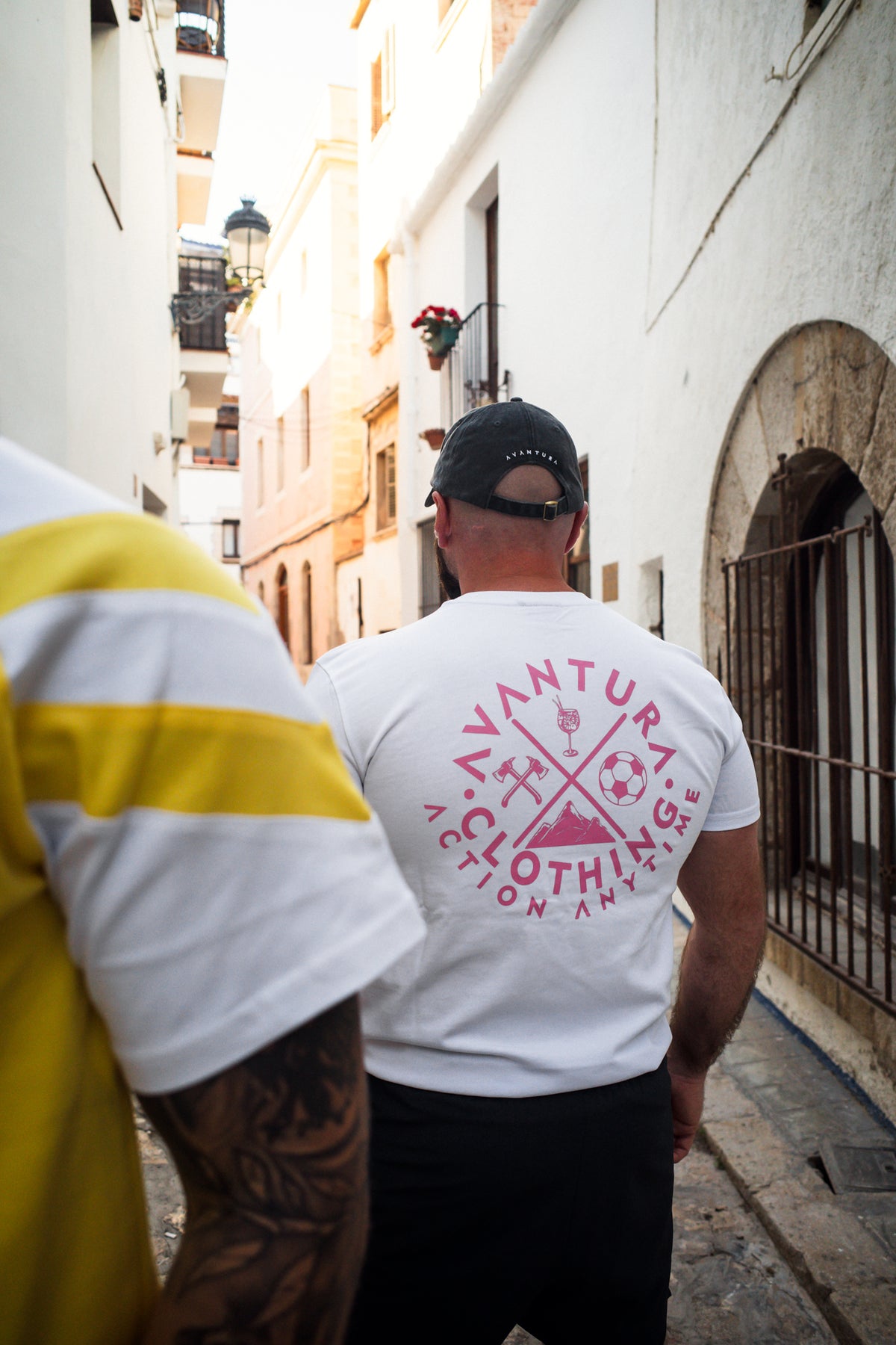 Rear view of white t-shirt displaying large pink graphic print with crossed icons
