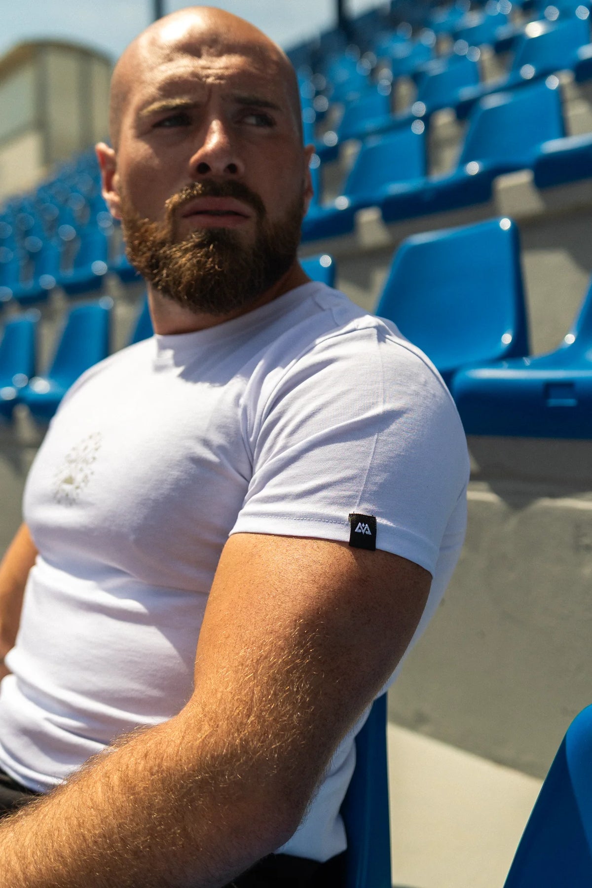 Close-up of white t-shirt sleeve showing woven label detail and chest graphic