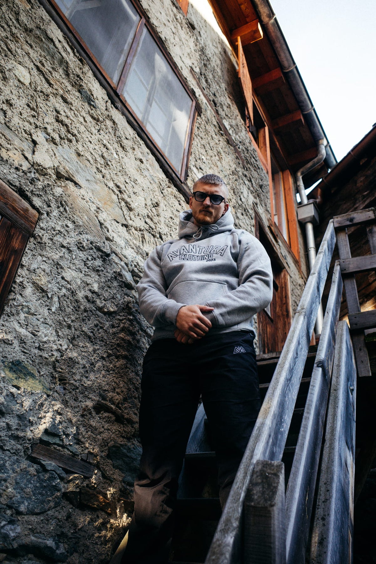 Unteransicht grauer Hoodie mit sichtbarem Logo auf Holzterrasse