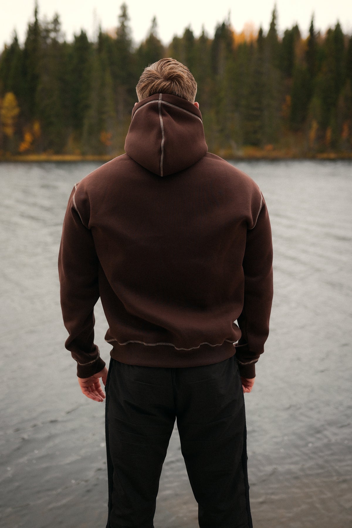 Back view of brown oversized hoodie with light contrast stitching on hood and hem