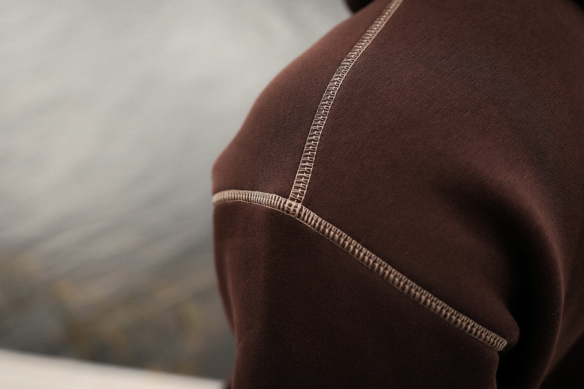 Close-up of fabric texture and light brown contrast embroidery on the brown hoodie