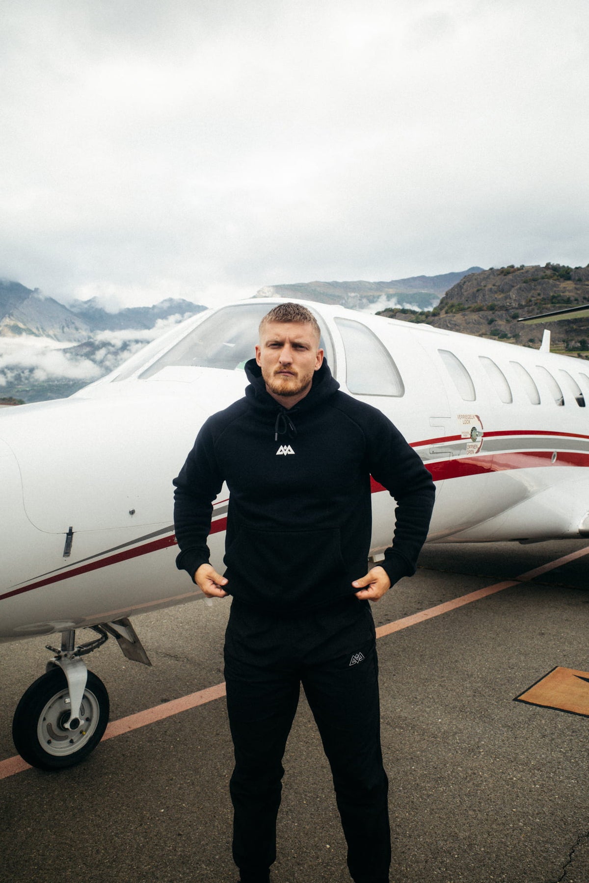 Schwarzer Hoodie Frontansicht mit kleinem Brustlogo und Kängurutasche