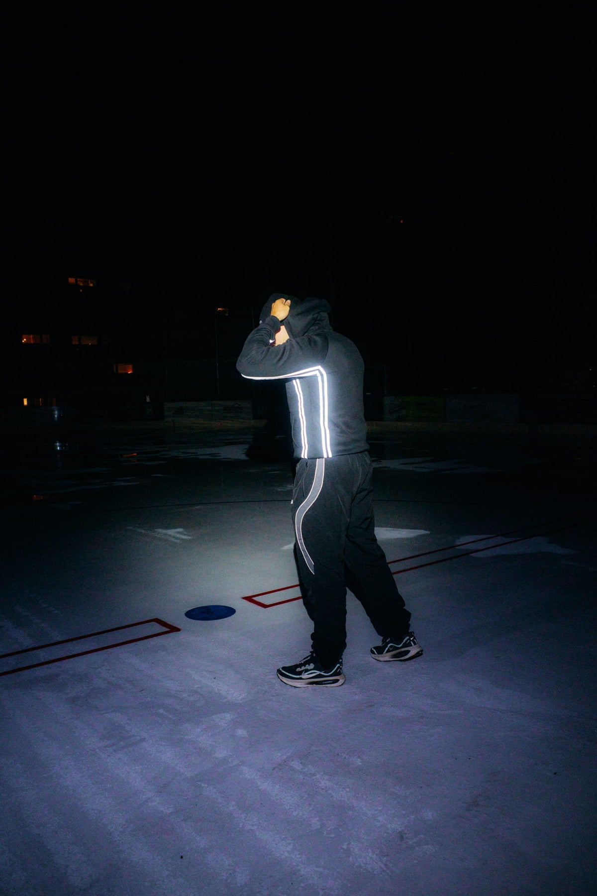 Black reflective hoodie with sleeve stripes worn at night