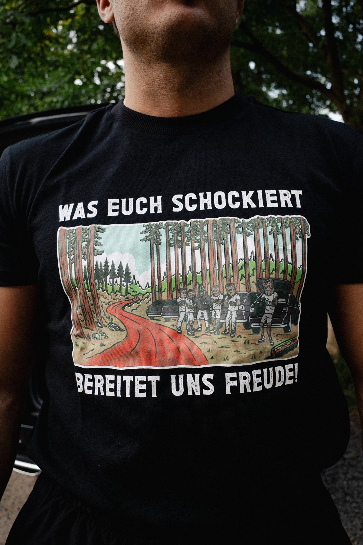 Black T-shirt front view highlighting detailed forest trail and vehicle illustration