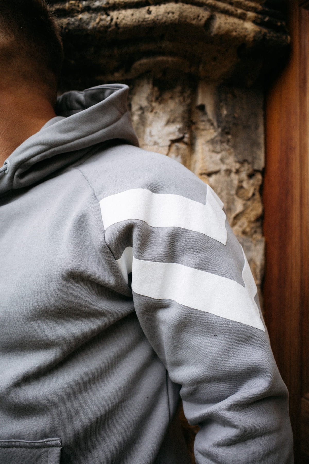Back view of the grey hooded sweatshirt with horizontal stripes across the sleeve