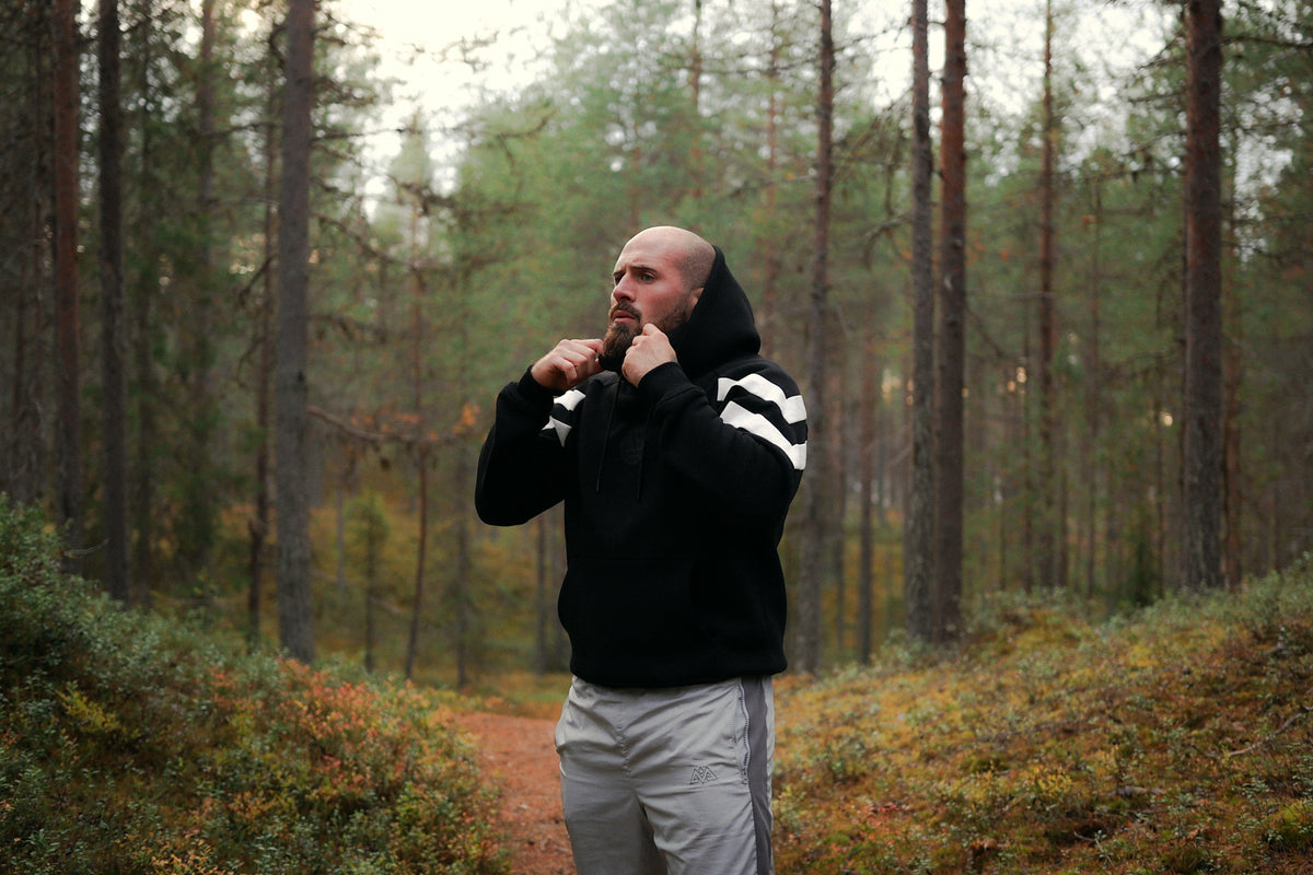 Mann trägt schwarzen Hoodie mit Kapuze im Wald