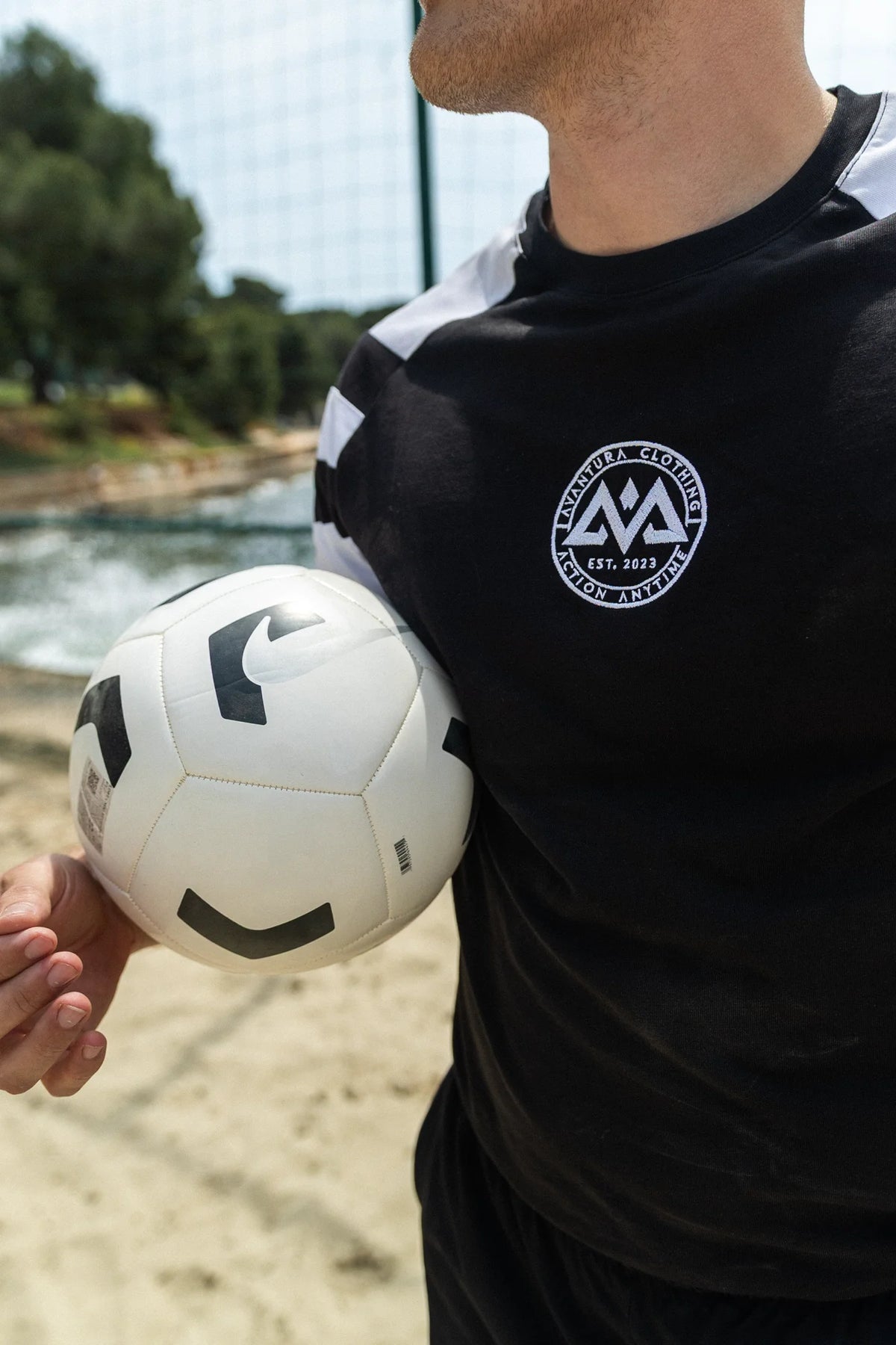 Black T-shirt with white shoulder stripes and chest logo close-up