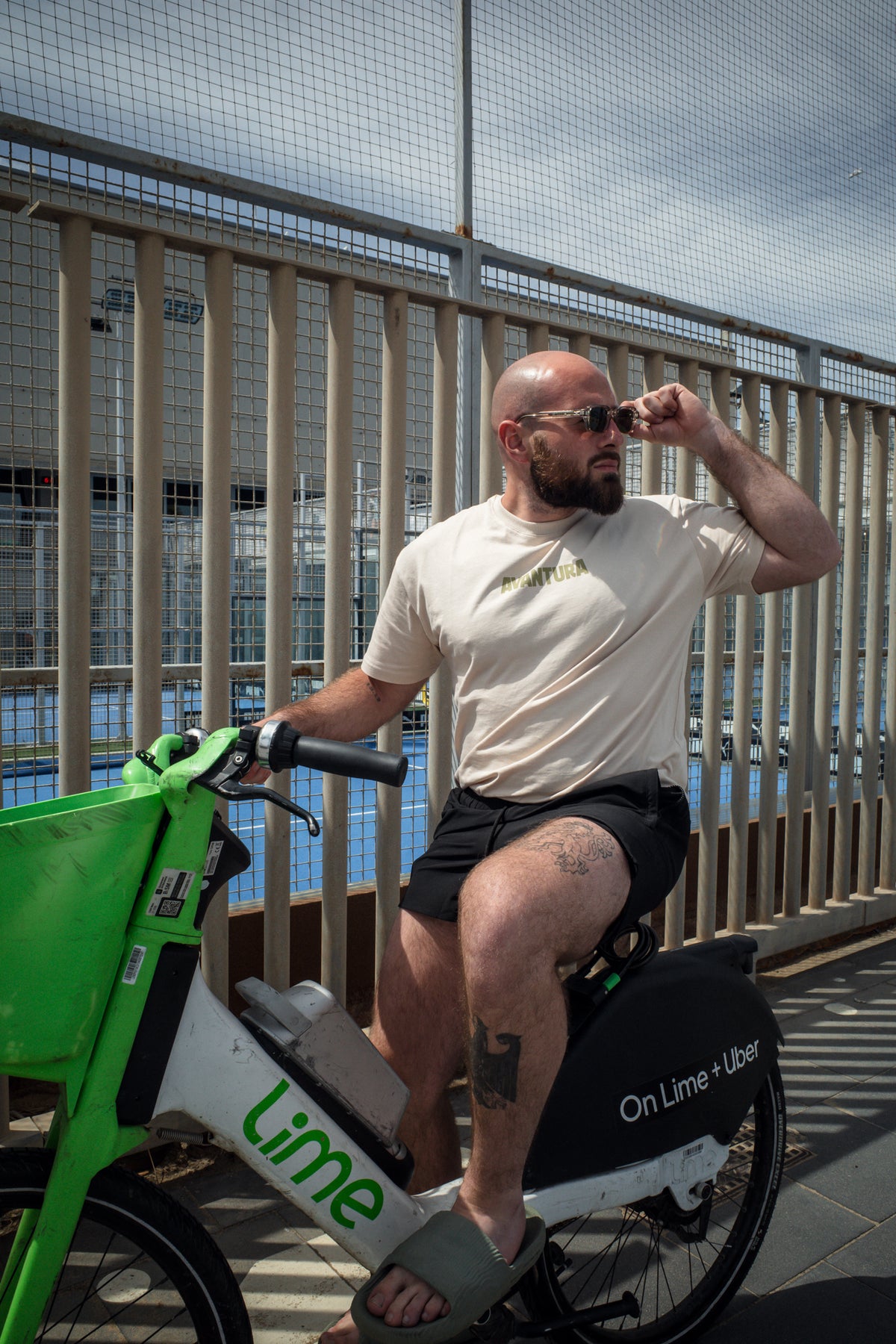 Man wearing cream oversized t-shirt with gold logo while cycling