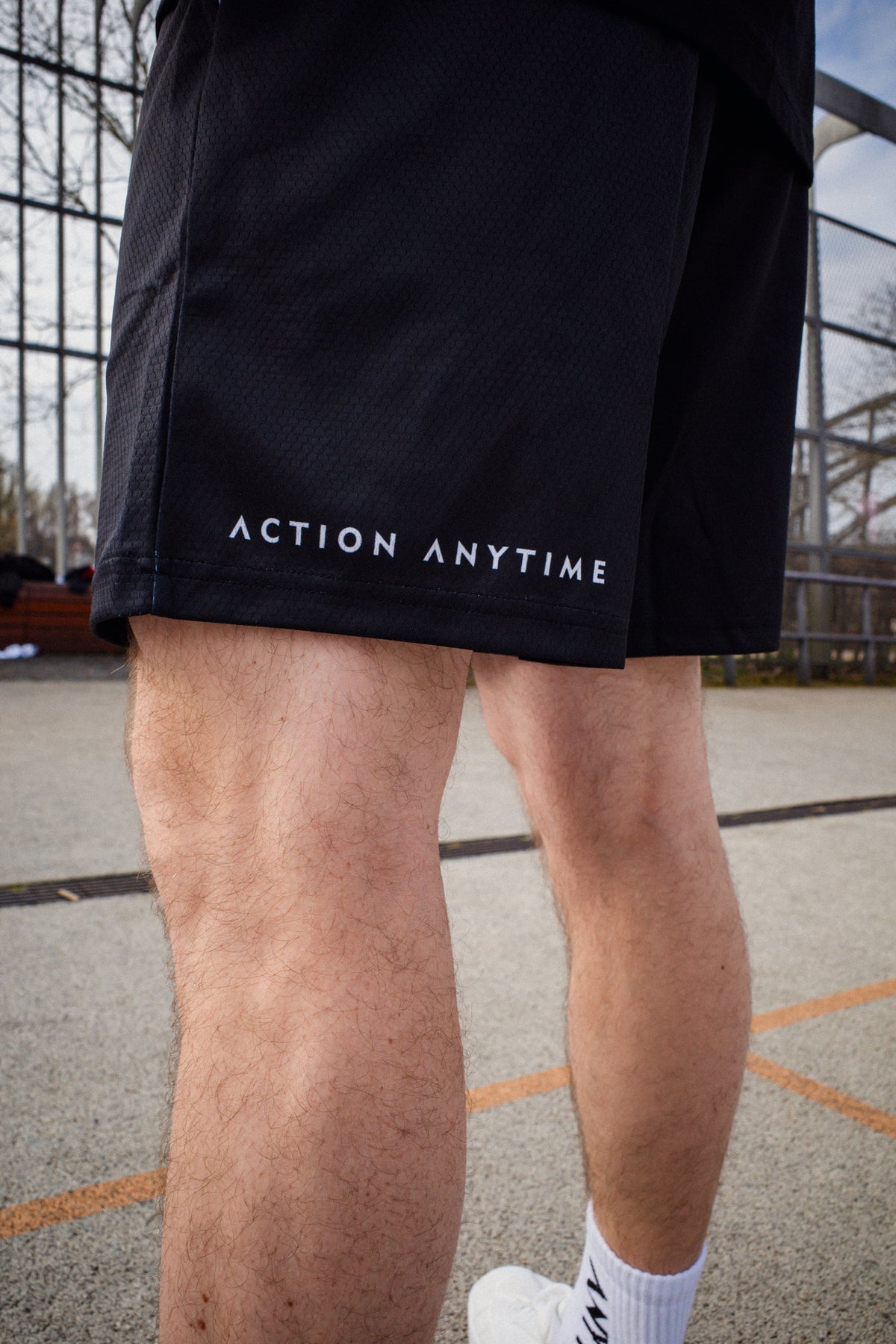 Back view of black shorts showing 'ACTION ANYTIME' hem print
