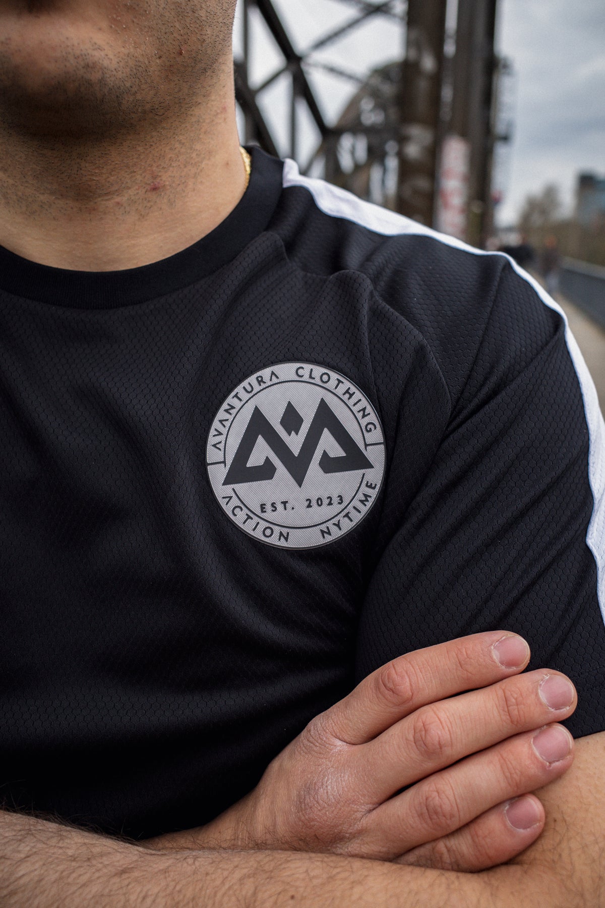 Close-up of Avventura Clothing patch logo on black mesh t-shirt