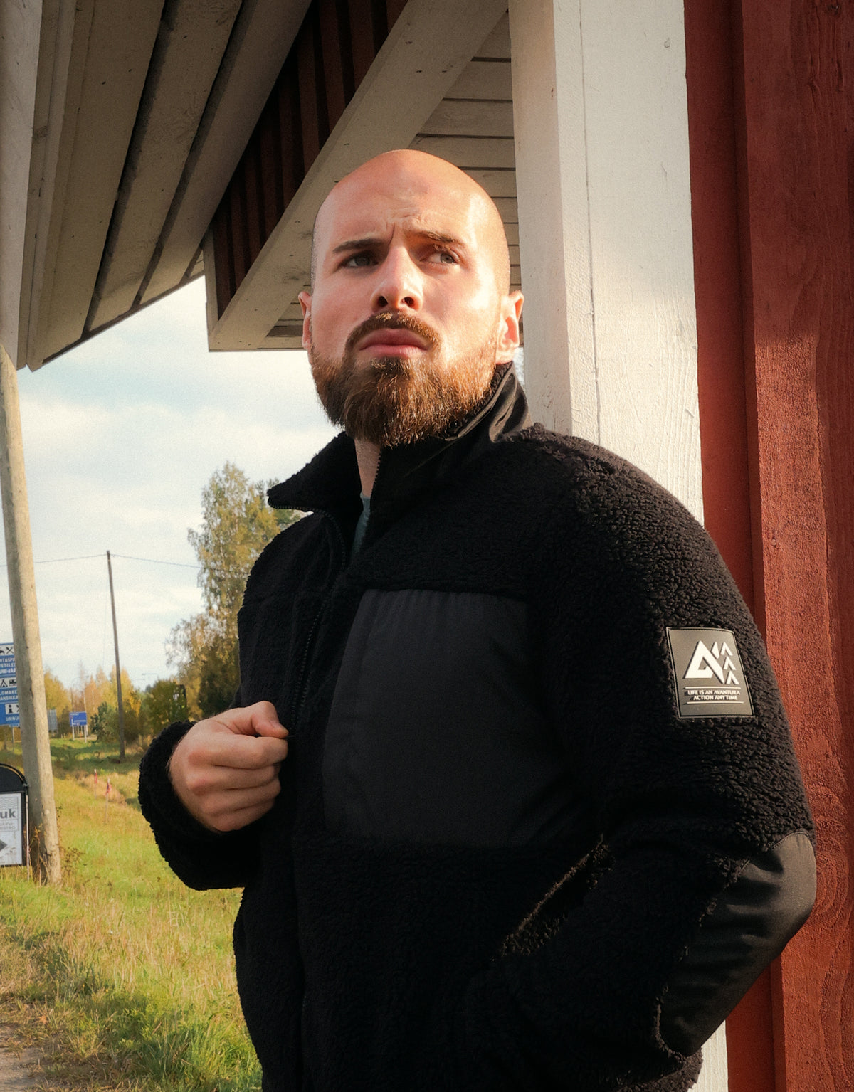 Black teddy fleece jacket with zippered front and logo patch on arm