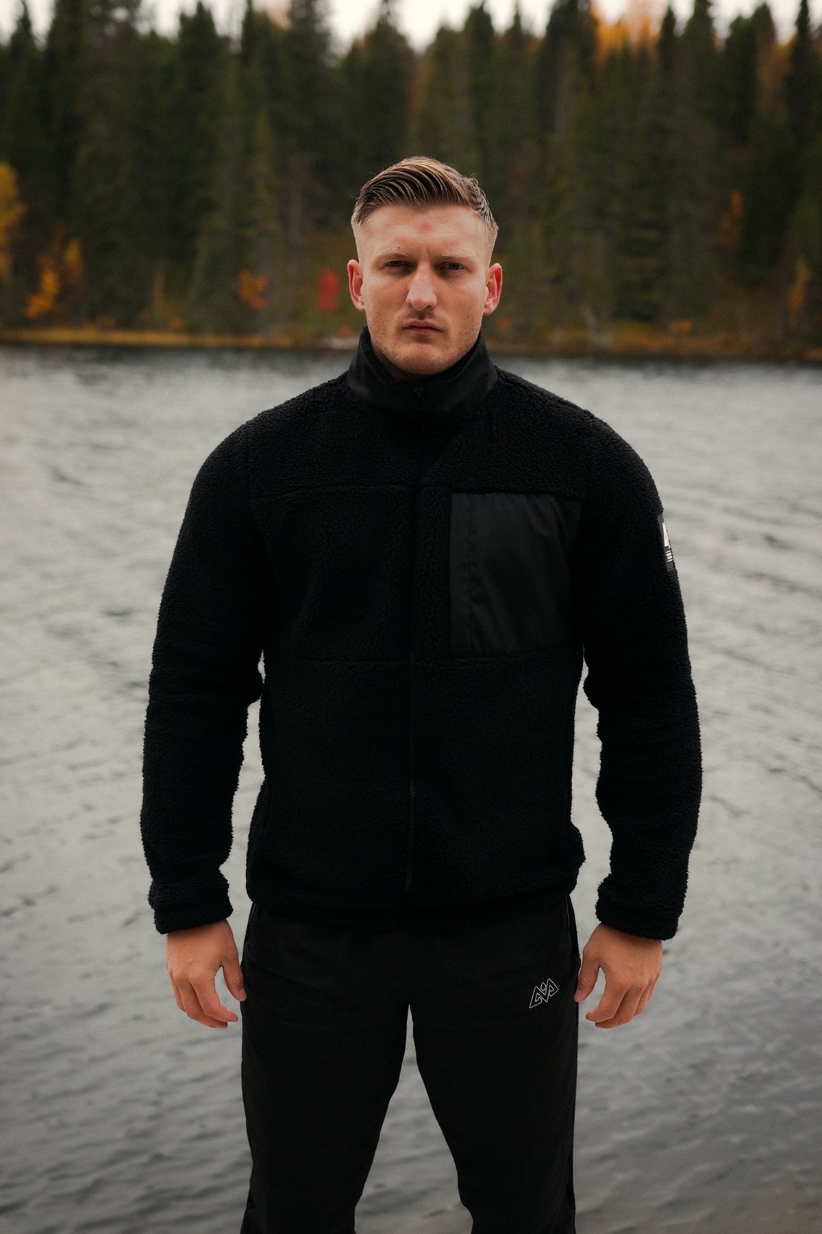 Front view of black full-zip teddy fleece jacket with chest panel and logo