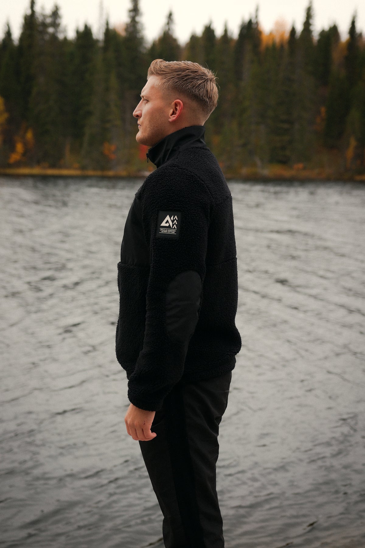 Black teddy fleece jacket with geometric logo patch and contrast fabric details