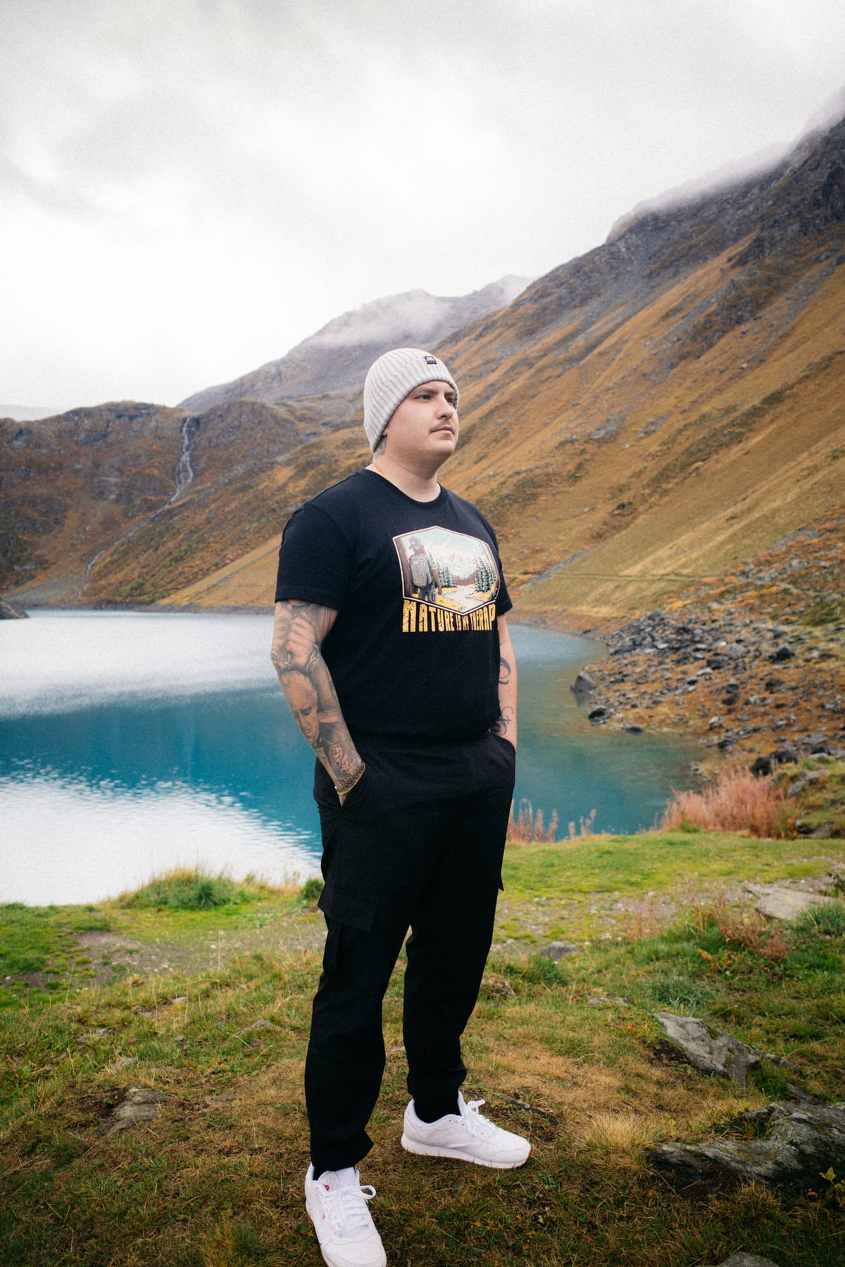 Profilansicht Mann im schwarzen T-Shirt an türkisfarbenem Bergsee
