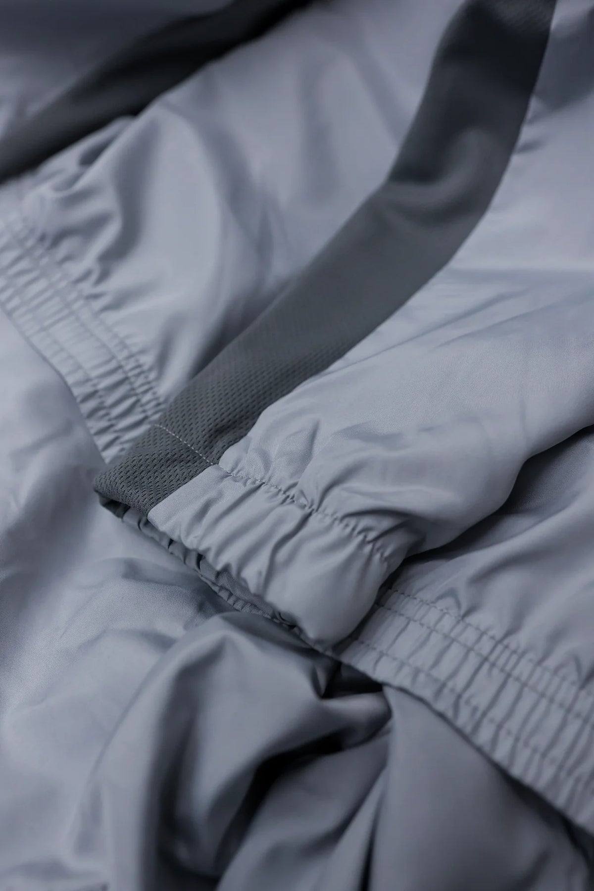 Macro shot of mesh side panel and elastic cuff on grey jacket