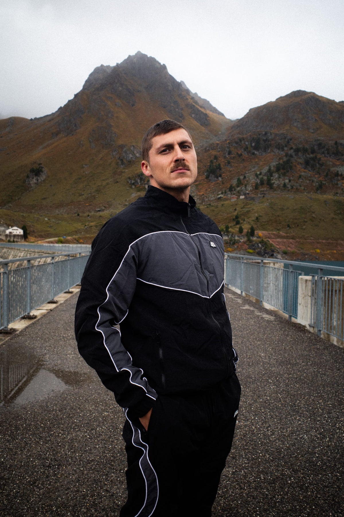Schwarze Trackjacke mit grauen Paneelen und weißen Streifen an den Ärmeln
