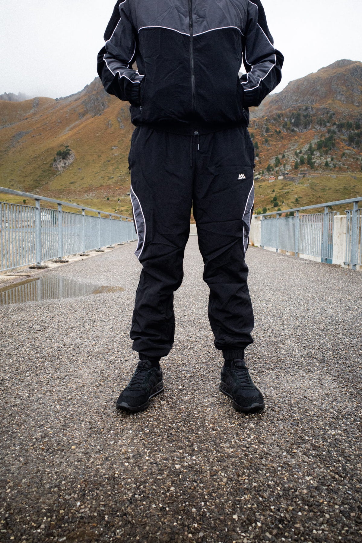 Schwarze Trackpants mit Beinabschlüssen und Sportschuhen