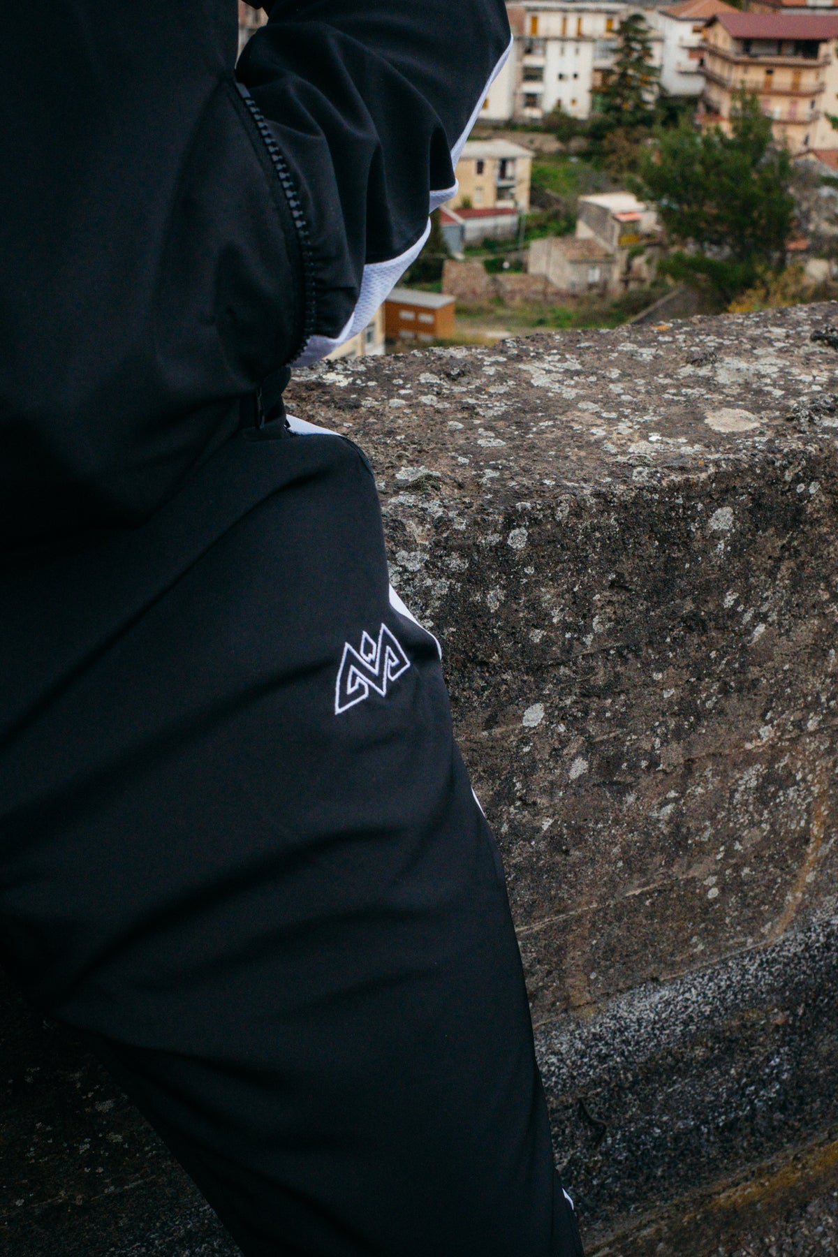 Seitenansicht des weißen Logos auf dem schwarzen Stoff der Trackpants