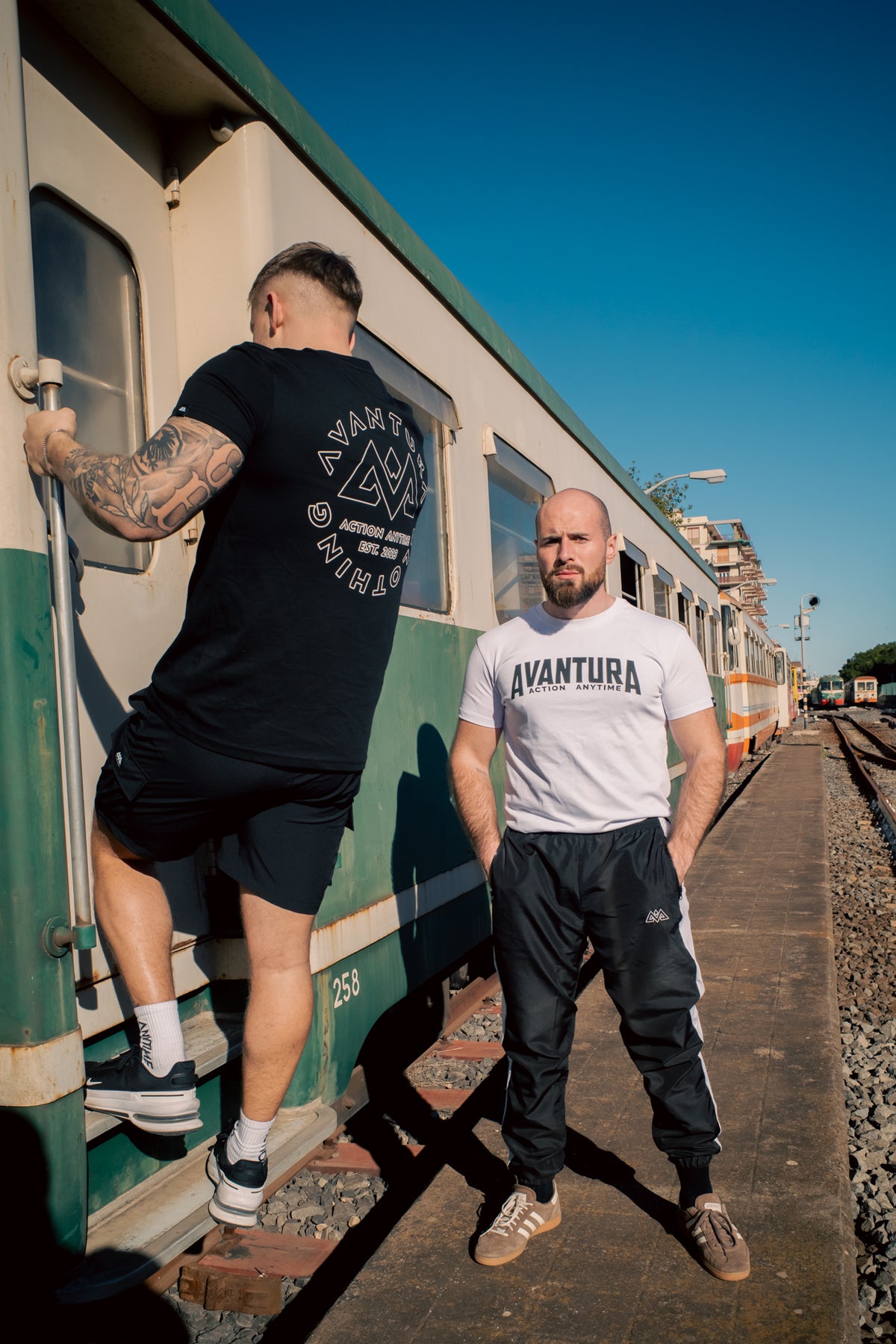 Schwarze Trackpants mit weißem Streifen im urbanen Setting am Bahnsteig