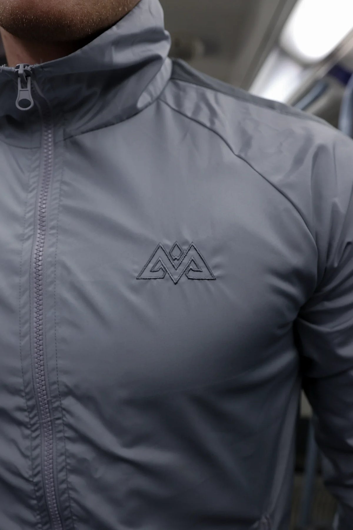 Detailansicht grauer Trainingsjacke mit gesticktem Brustlogo