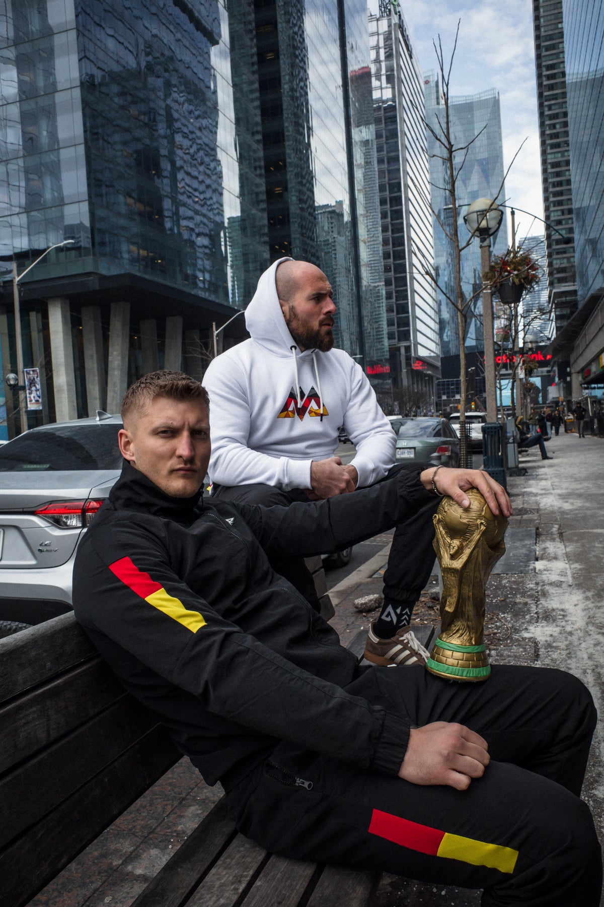 Schwarzer Trainingsanzug mit rot-goldenen Akzenten, goldene Trophäe auf Bank