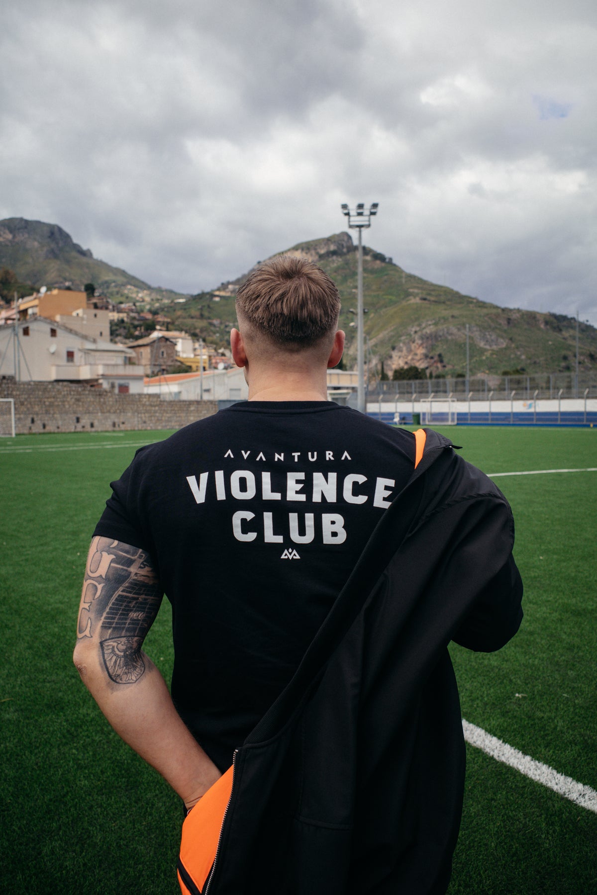Schwarzes T-Shirt mit großem Backprint und orangefarbener Jacke