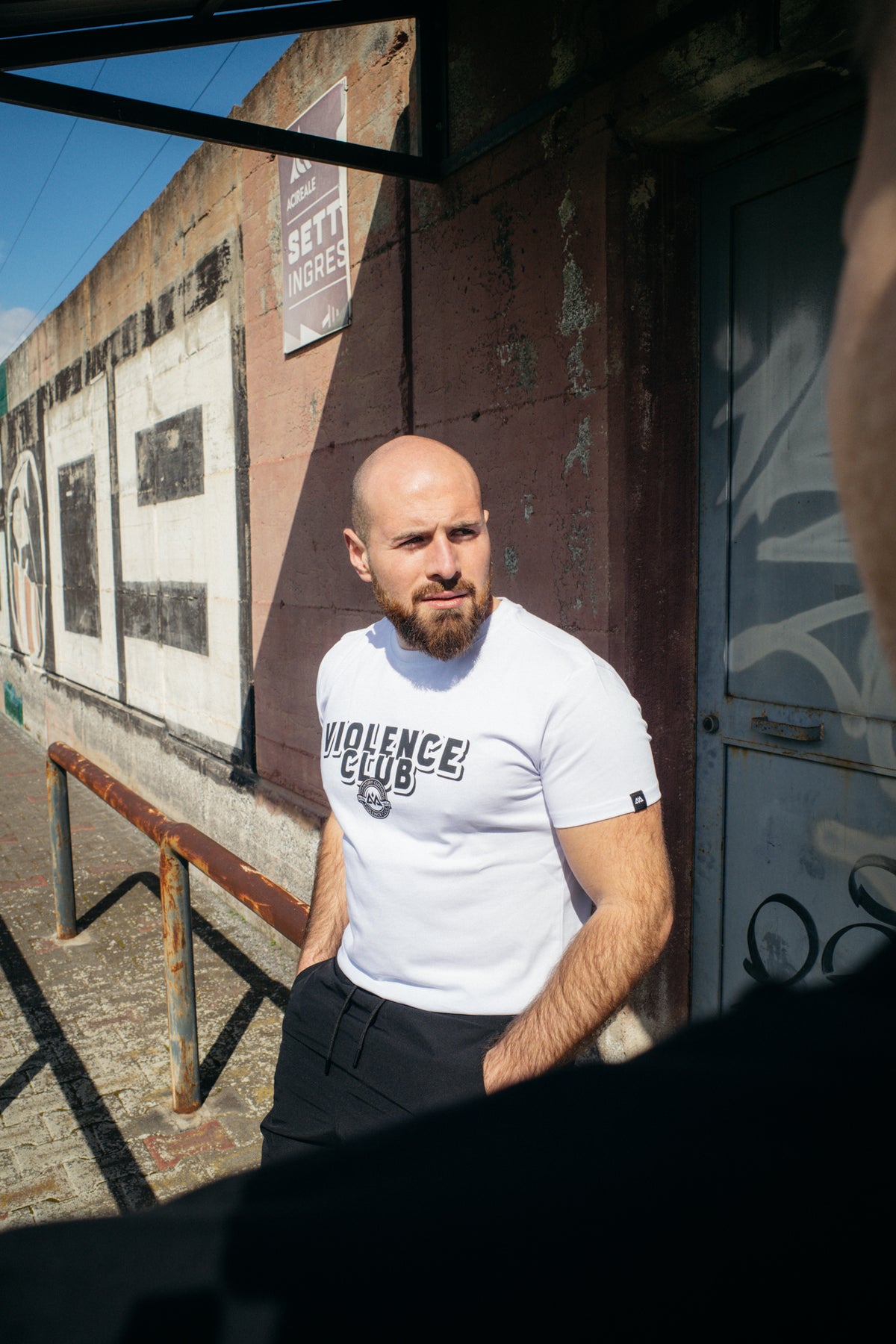 Men's white short-sleeve T-shirt with bold black typography and circular crest