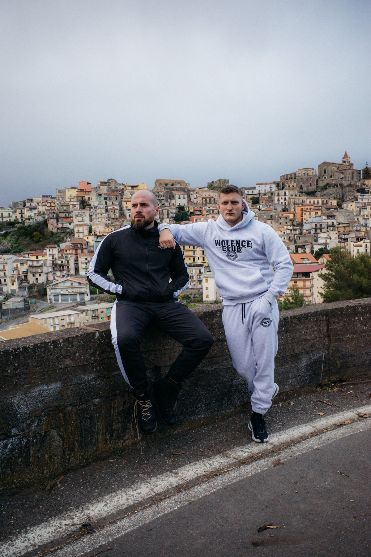 Grauer VIOLENCE CLUB Hoodie mit Jogginghose in städtischer Umgebung