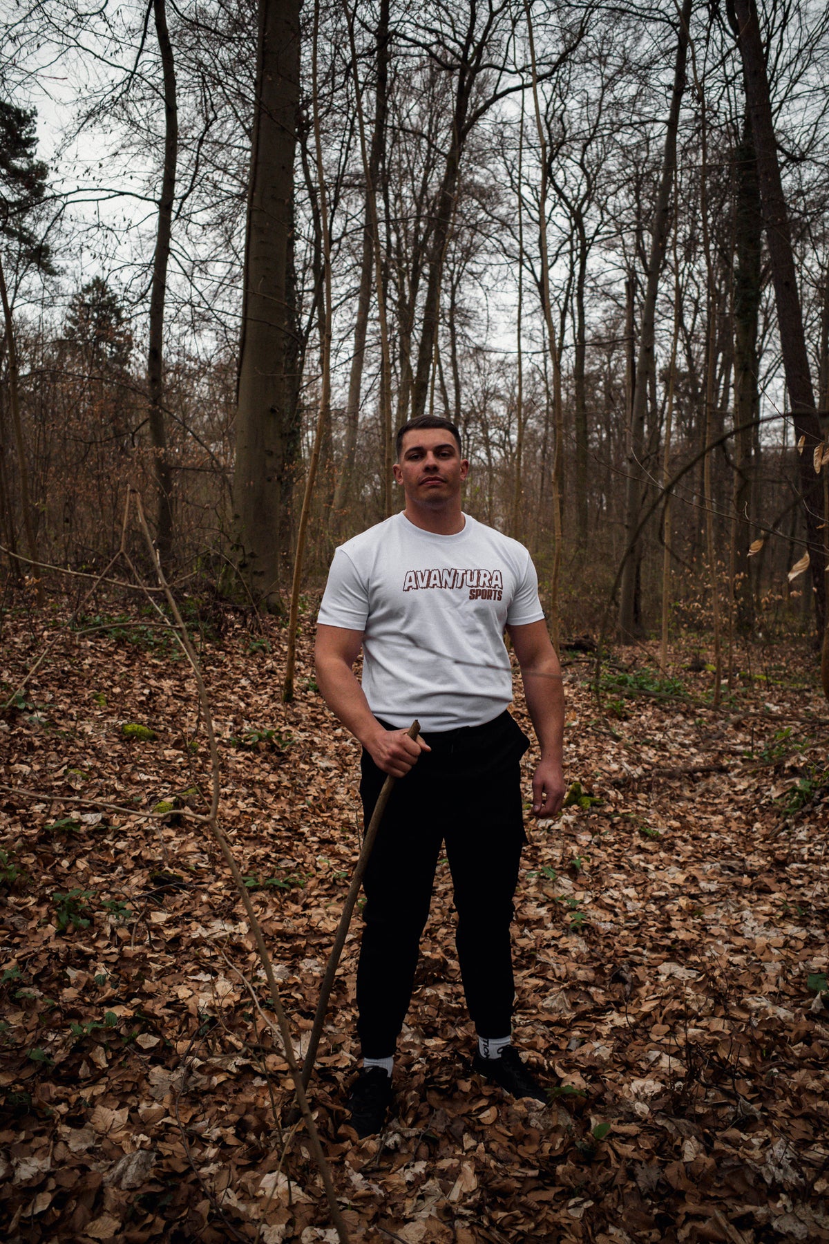 Front view of white crew-neck T-shirt with centered brown AVANTURA SPORTS logo