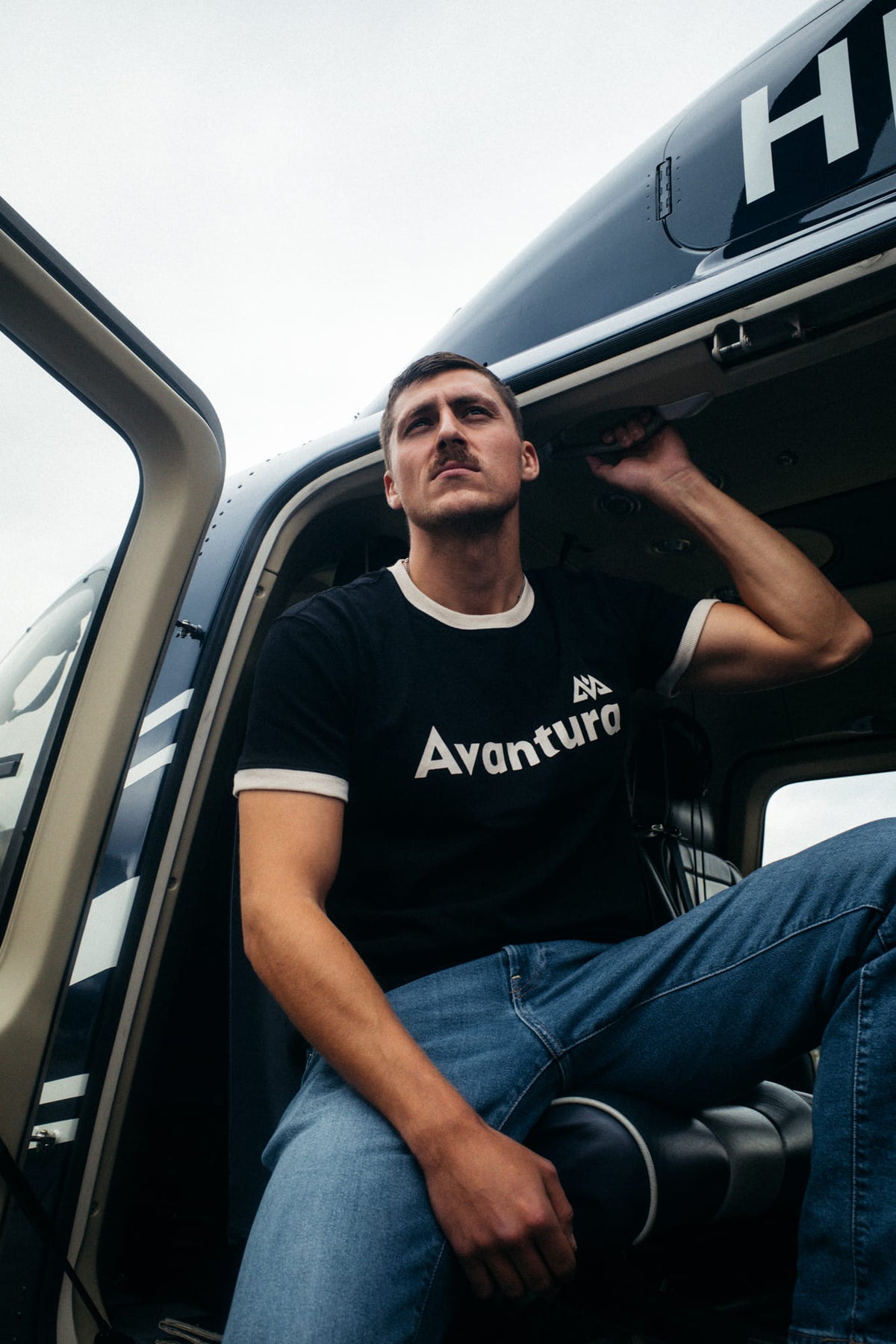 Mann trägt Avantura T-Shirt Schwarz im Helikopter, Lifestyle-Fit
