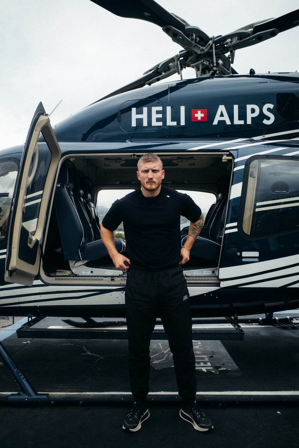 Mann trägt schwarzes Oversized T-Shirt in freier Natur vor Hubschrauber