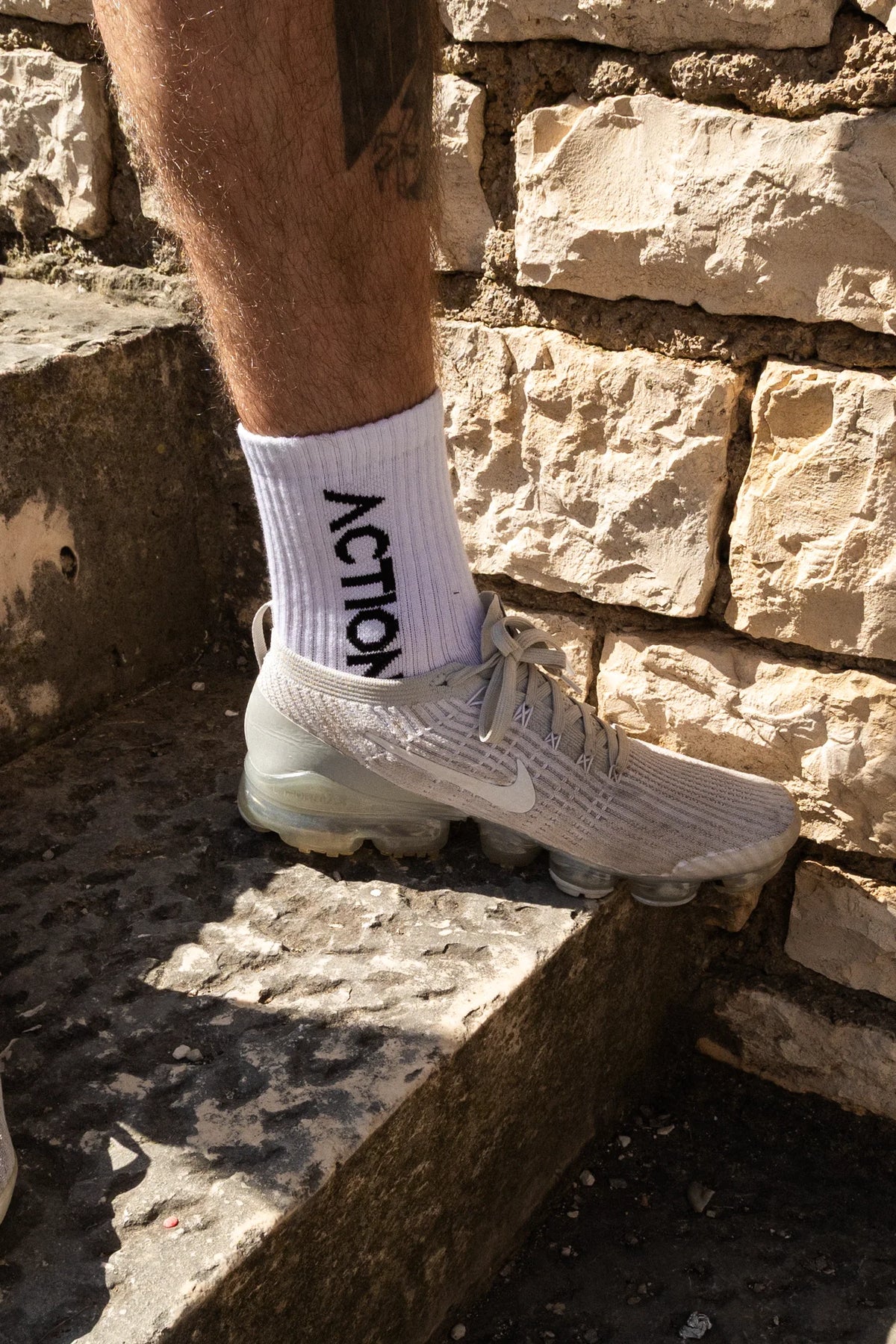 White ribbed crew sock featuring bold vertical 'ACTION' print