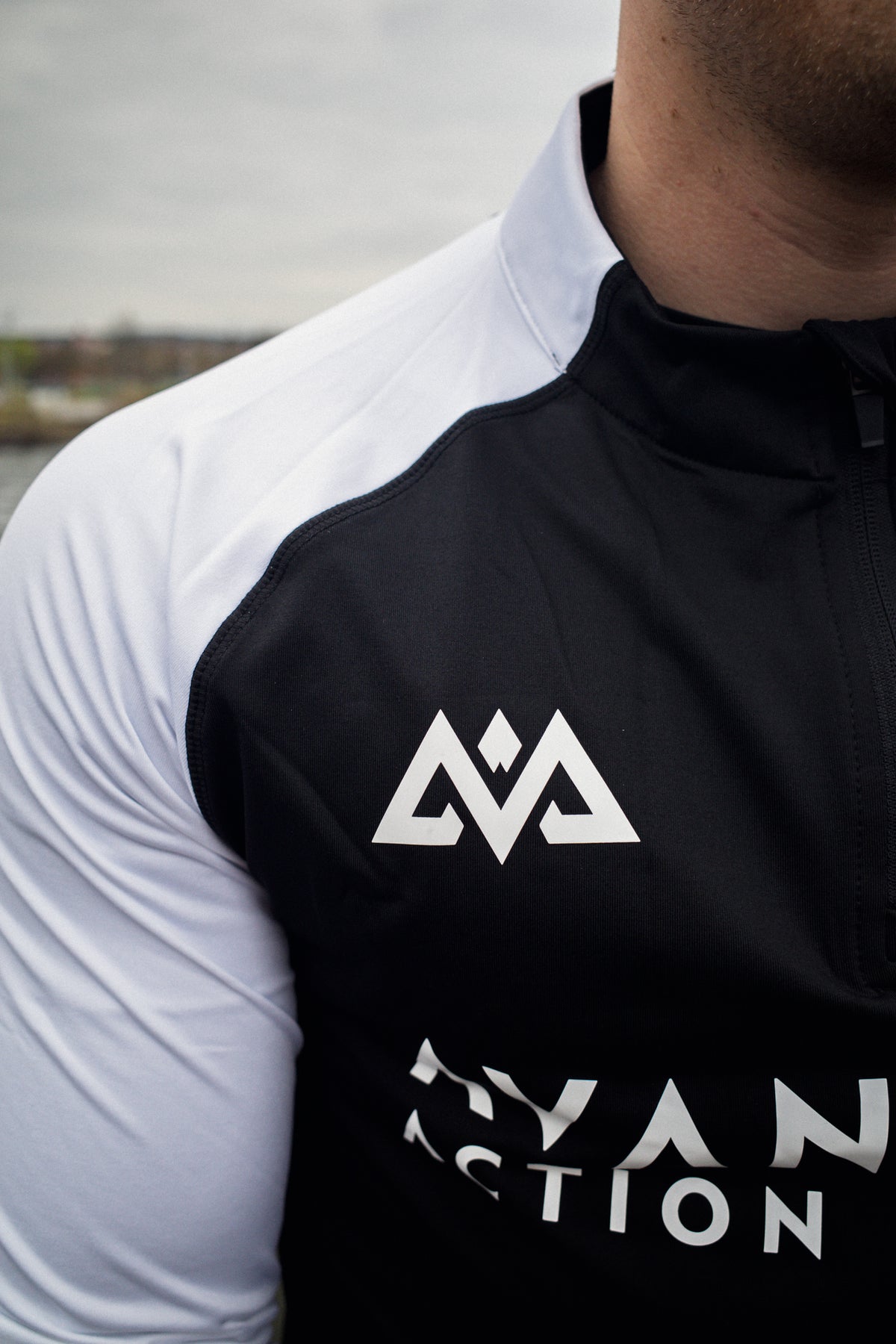 Nahaufnahme weißes geometrisches Logo auf schwarzem Halfzip-Sweater Brustseite