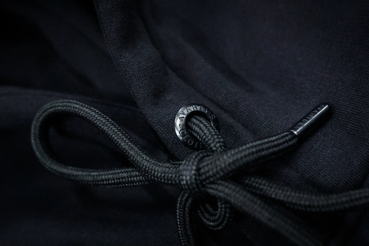 Detailaufnahme der gravierten Metallöse und gewebten Kordel am schwarzen Hoodie