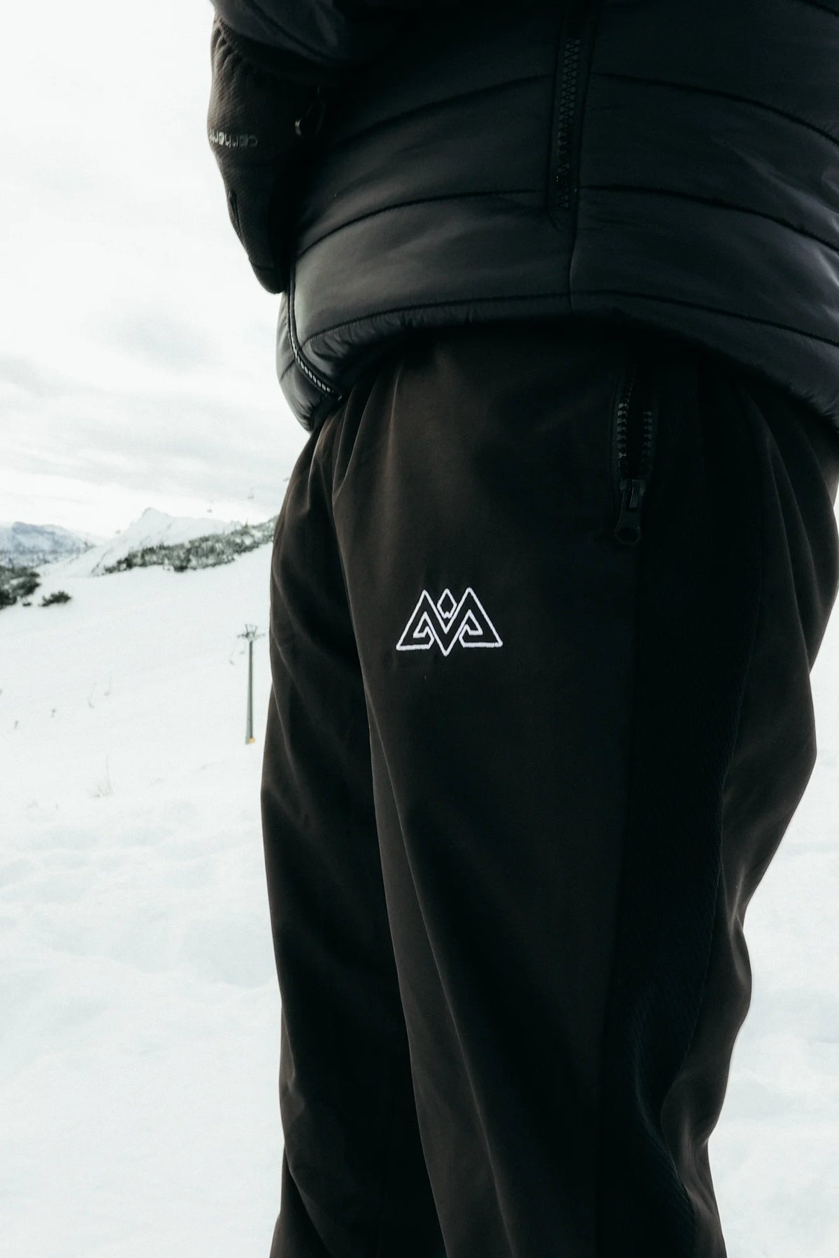 Black tracksuit pants with white embroidered logo and zippered side pocket