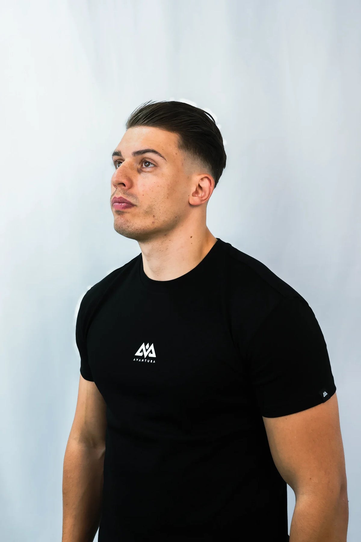 Front view of black Avantura T-shirt showing small chest logo and tailored fit