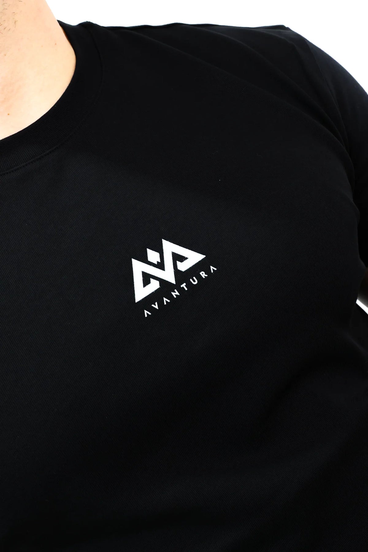 Macro shot of white Avantura brand logo printed on black T-shirt fabric