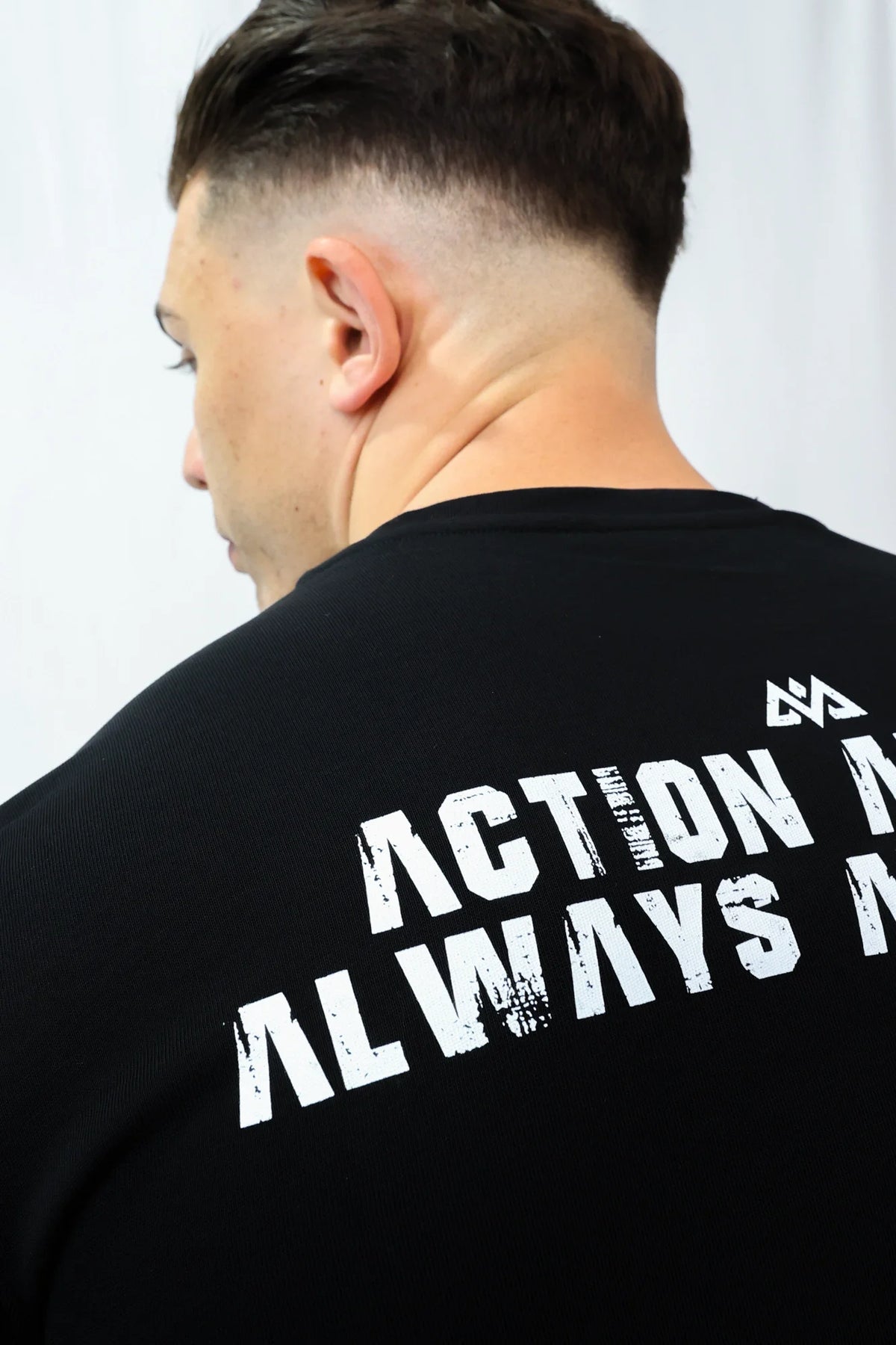Close-up of distressed white graphic print and geometric logo on black T-shirt back
