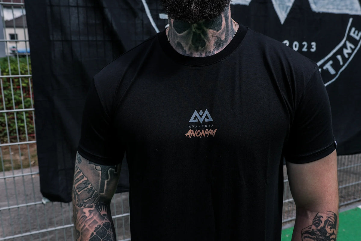 Detail of orange script logo on black crew neck T-shirt