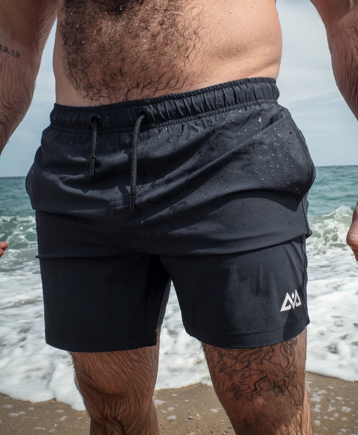 Navy blue swim trunks with white logo on rear leg