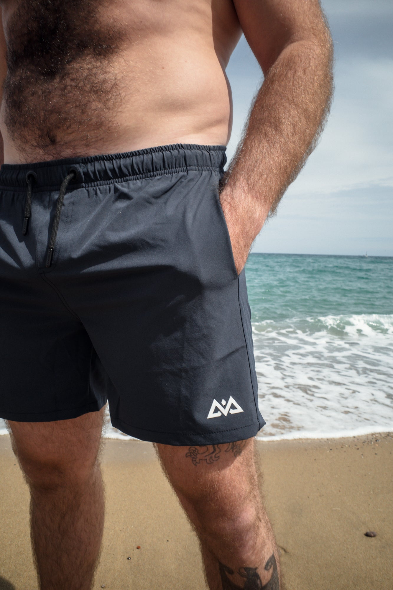 Hand in side pocket of navy swim trunks