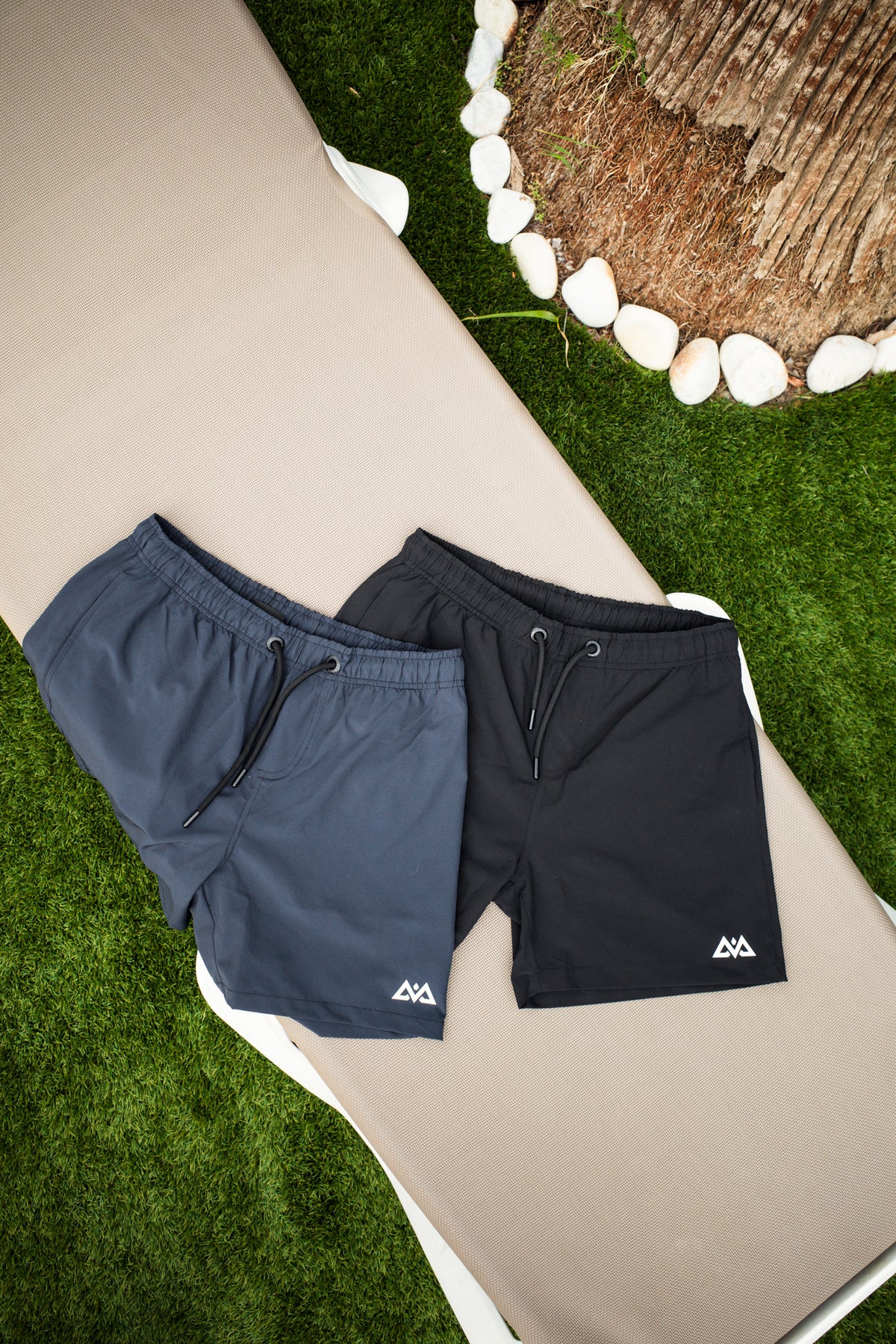 Navy and black swim trunks laid out on lounge chair