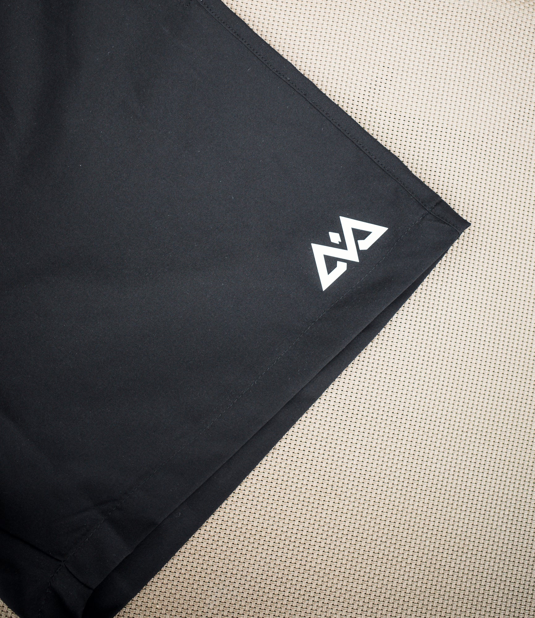 White geometric logo print detail on black swim short hem