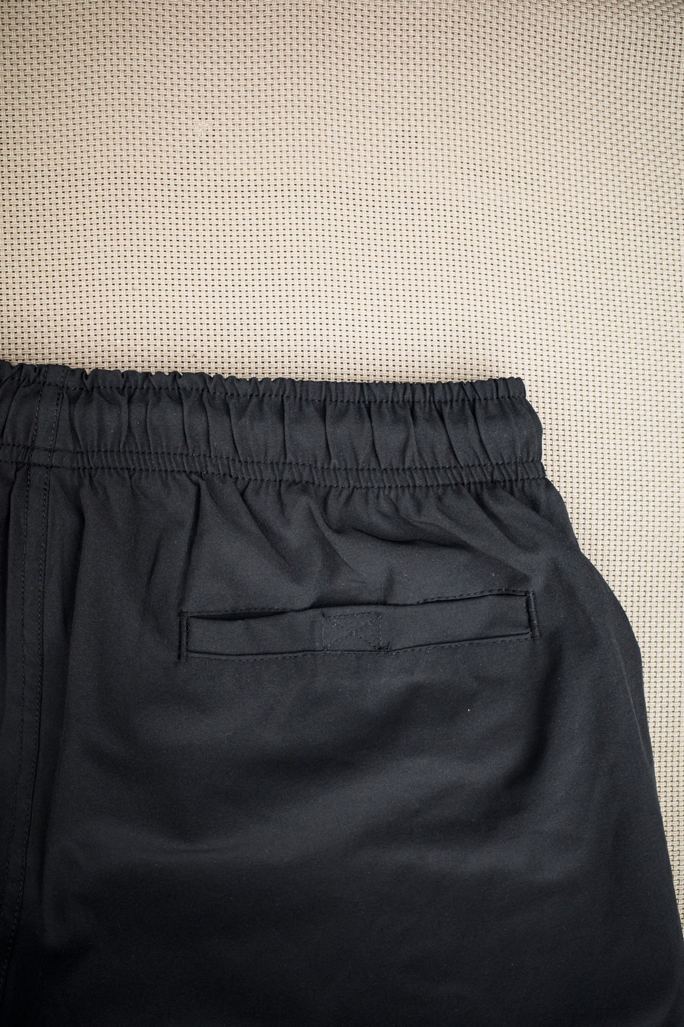 Hook-and-loop back pocket detail on black swim trunks