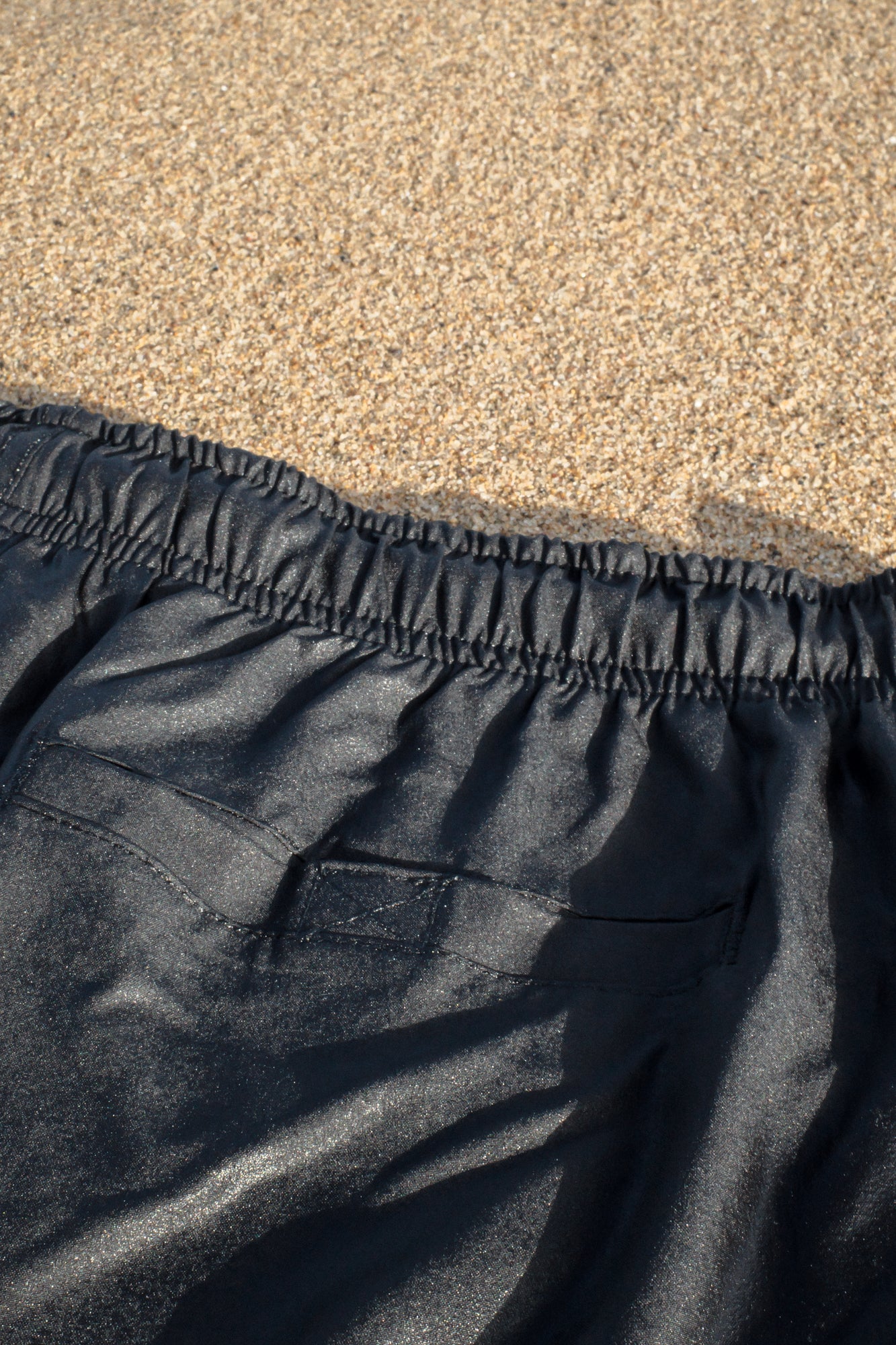 Back pocket and waistband detail of black swim trunks